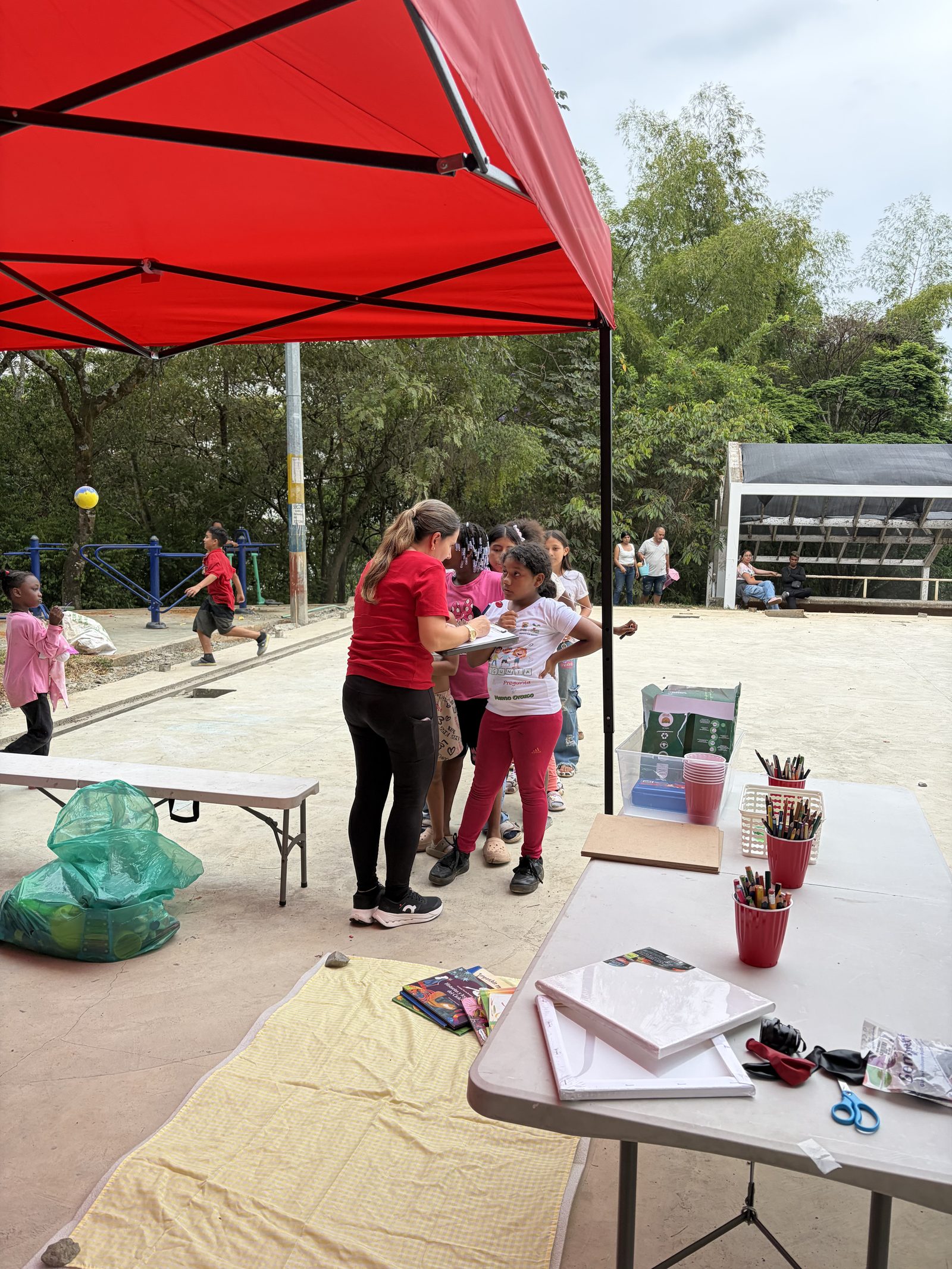 Mesa de trabajo bajo la carpa con colores, cuadernos y tijeras organizados antes de la sesión